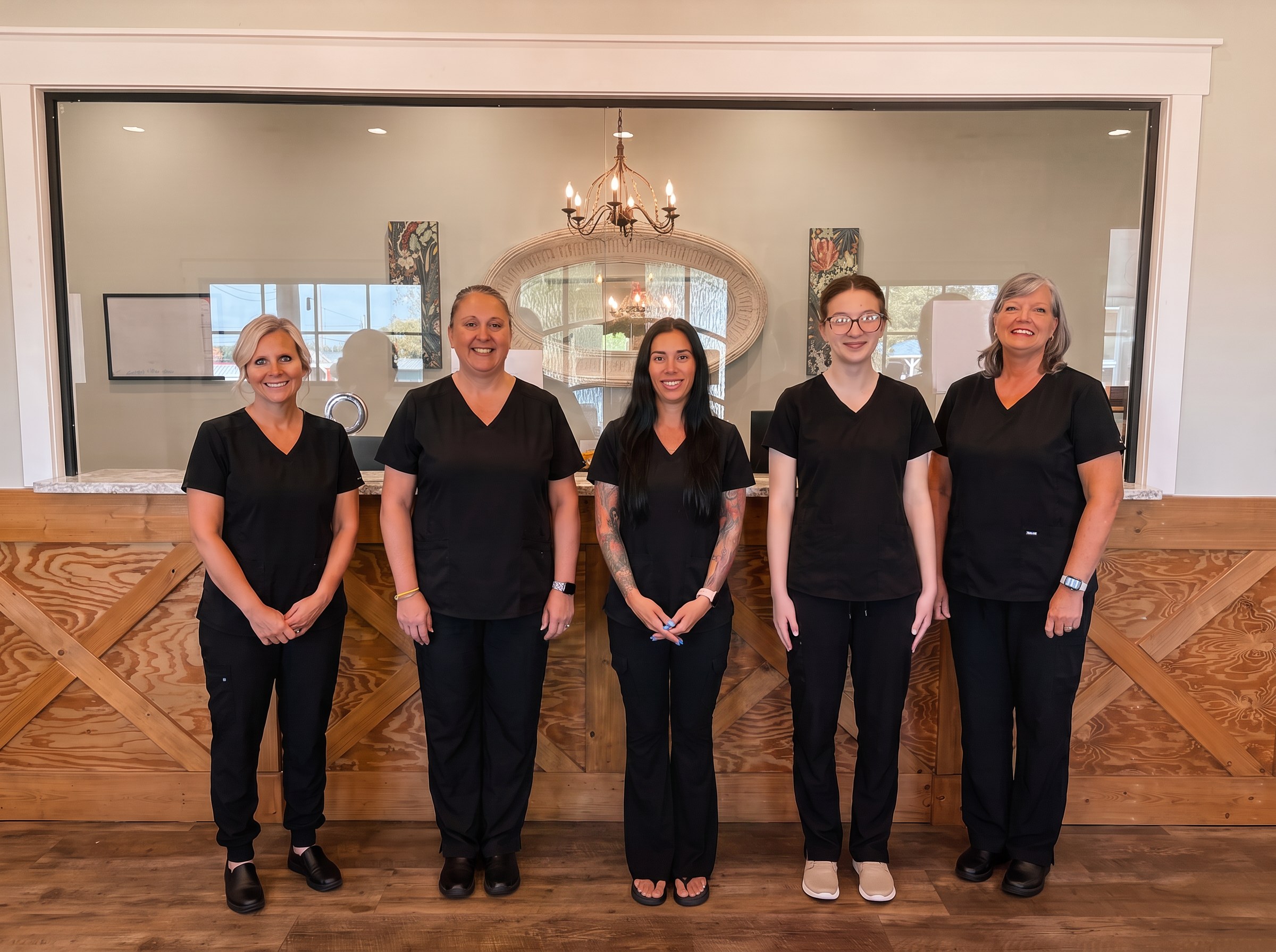 The Qualls Harbin Family Medicine front-office and clinical team standing together at the front desk.